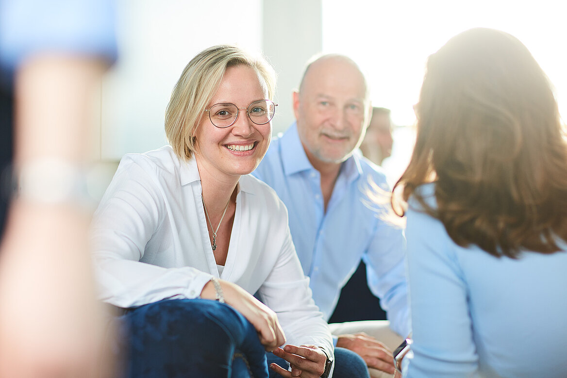 Drei Personen sitzen zusammen und unterhalten sich freundlich.