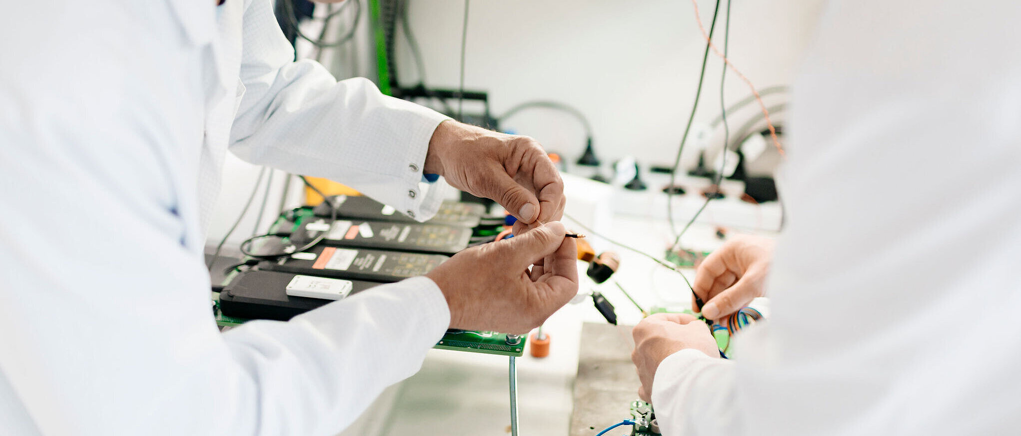 Zwei Personen in weißen Laborkitteln arbeiten gemeinsam an einem Prüfstand.