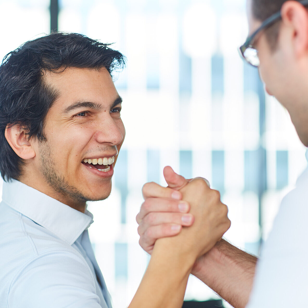 Zwei lächelnde Männer geben sich die Hand.