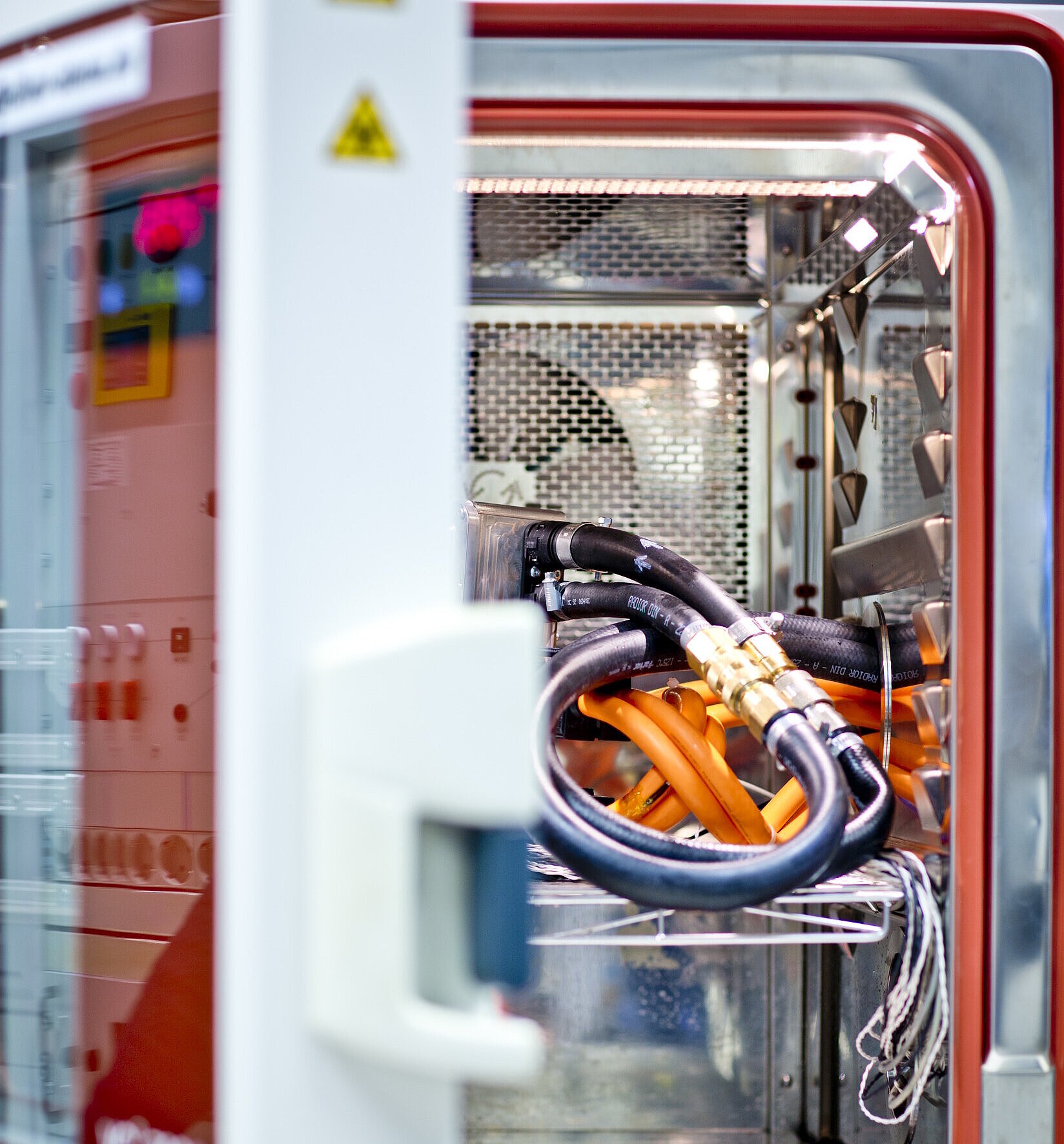 Geöffnete Klimakammer mit Kabeln und Prüflingen für Temperatur- und Umwelttests.