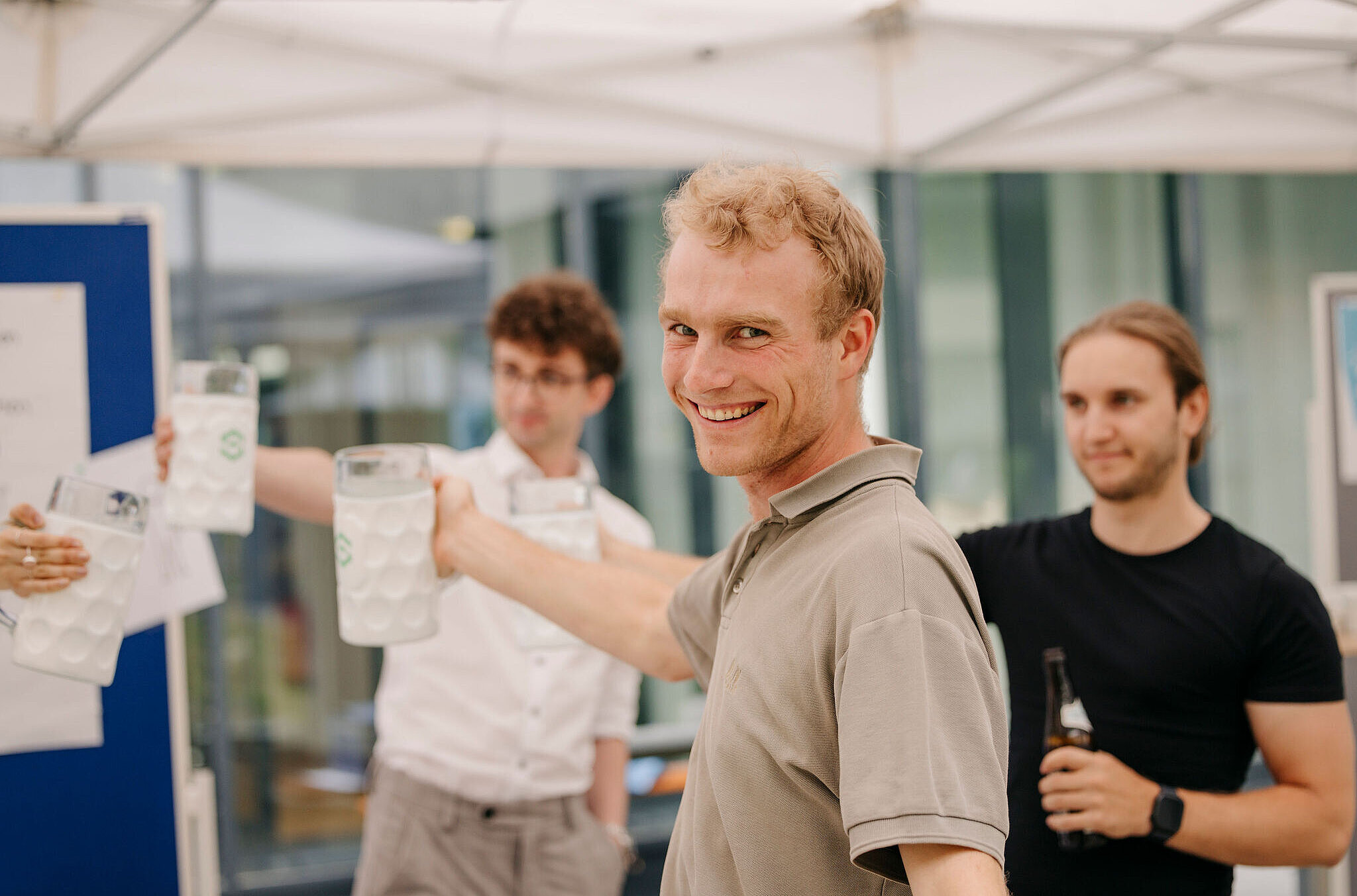 Mehrere Personen stoßen bei einem Betriebsfest mit Getränken an und lächeln in geselliger Atmosphäre.