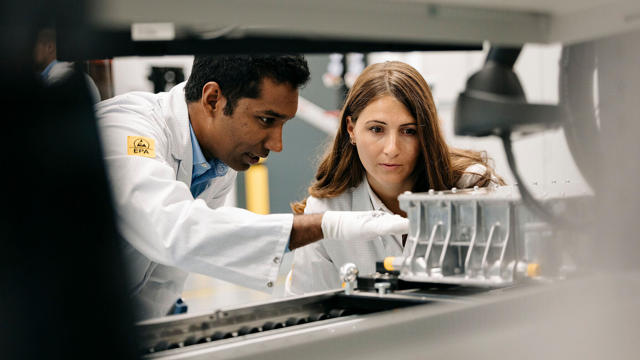 Zwei Personen in Laborkleidung prüfen gemeinsam ein Steuergerät an einem Prüfstand.