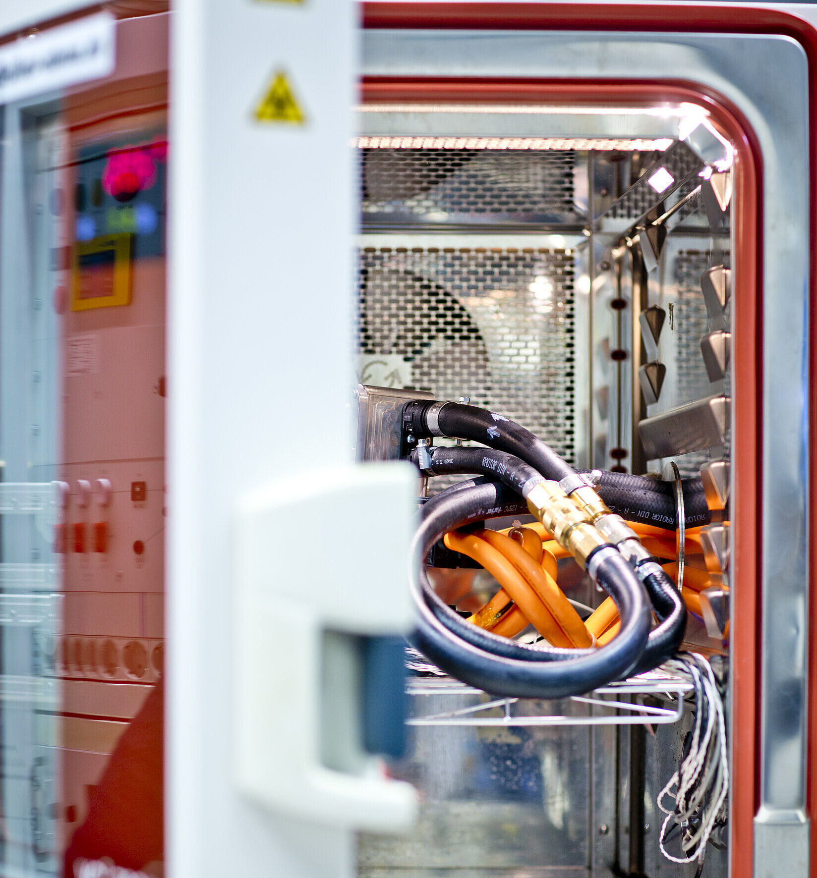 Geöffnete Klimakammer mit Kabeln und Prüflingen für Temperatur- und Umwelttests.