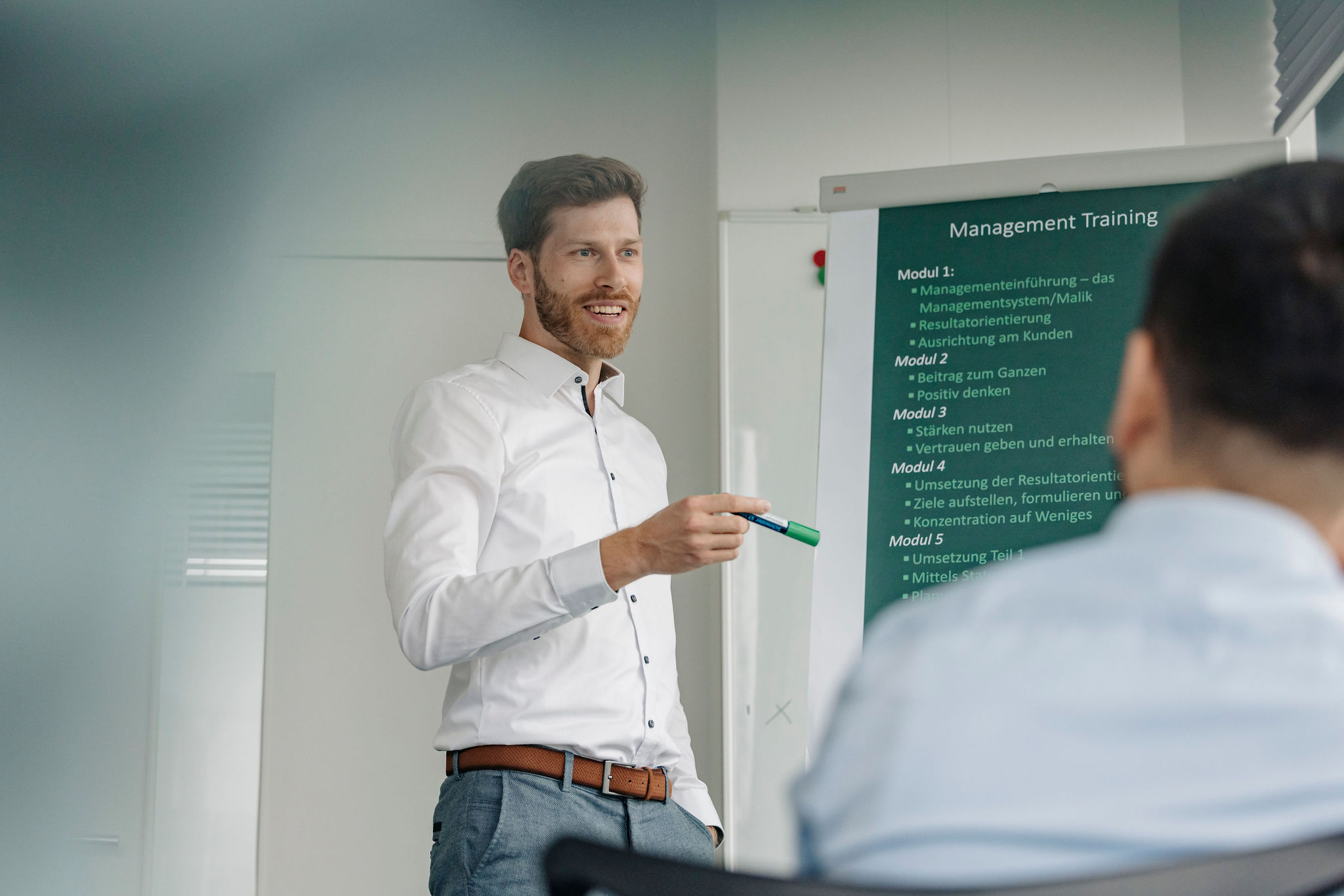 Person steht vor einem Flipchart und erklärt Inhalte eines Trainings in einer Schulungssituation.