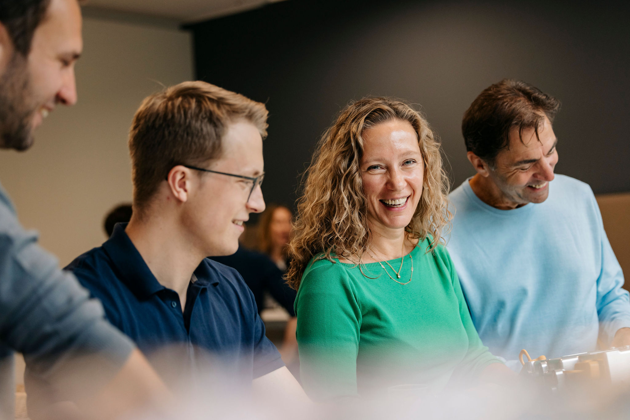 Vier Personen sitzen zusammen, lachen und unterhalten sich in einer freundlichen Runde.