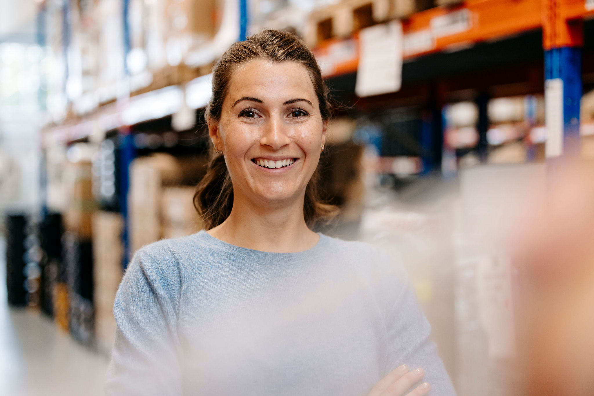 Mitarbeiterin von Silver Atena im Logistikbereich vor Lagerregalen.